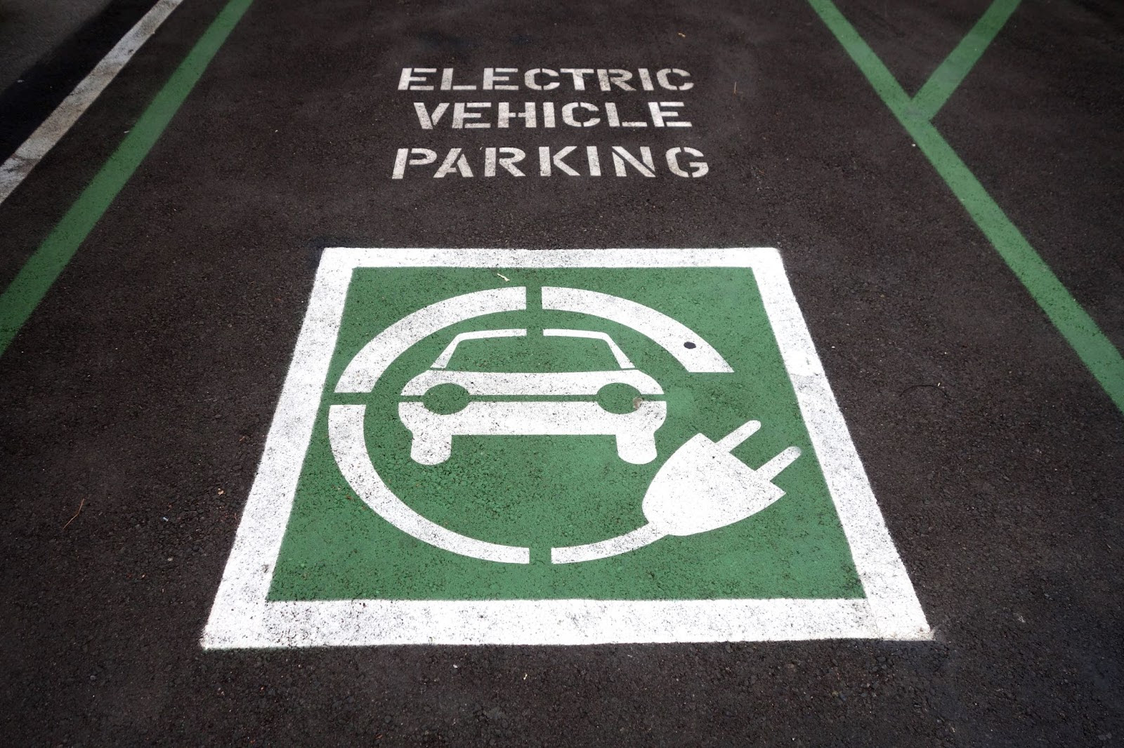 A parking lot with a sign and an electric vehicleDescription automatically generated
