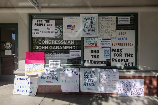 Deadline for Democracy signs on Garamendi's Davis office window: "For the People Act- Voting rights= democracy"; "Save voting rights for America- Deadline for Democracy www.indivisible.org"; "Pass the for the People Act now!" "Filibusters are undemocratic- Pass the For the People Act- end the filibuster now!"; "For the People act- Protects voting rights, ends gerrymandering, campaign $$$ limits"; "Protect our right to vote"; "Stop voter suppression"; "We demand democracy for the people"; "End the filibuster"; "Pass the For the People Act"; "We must protect our right to vote!"; "For the People"; "Pass the For the People Act, Pass the John Lewis Voting Rights Act, End the undemocratic Senate filibuster, say NO to voter suppression"; "Thank you Senator Padilla" and "Pass the For the People Act Now!"