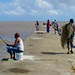 Fishing is a regular activity on the sea wall and on Sundays even more so. The man in the background to the left if pulling a trawling net, very hard work indeed. Georgetown, Guyana, South America. by NigelDurrant