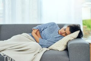 Woman unwell lying on a sofa with a blanket