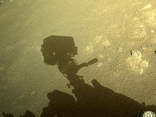 Perseverance rover shows the shadow of its camera “head” being cast on the dusty surface on Mars.