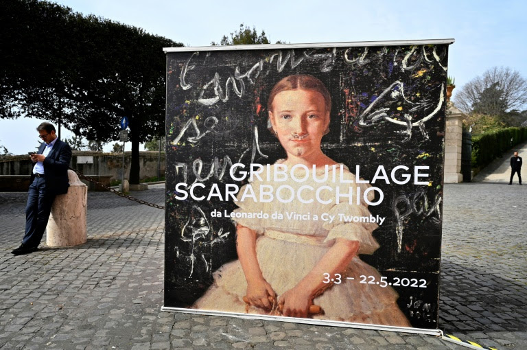 Um visitante ao lado do cartaz da exposição