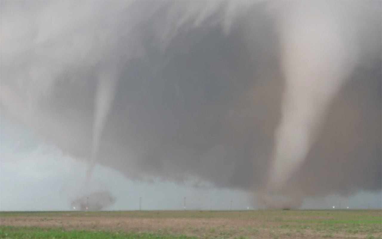 two tornadoes spin almost side-by-side under a dark cloud.