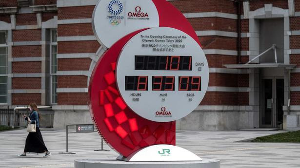 People walk near a countdown clock for the Tokyo 2020 Olympic and Paralympic Games outside Tokyo station in Tokyo on April 13, 2021.