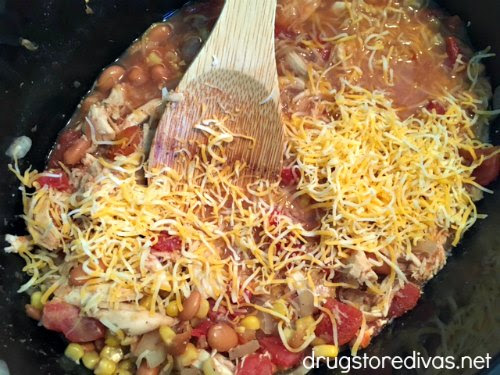 Slow Cooker Chicken Burrito Bowl ingredients, and a spoon, in a slow cooker.
