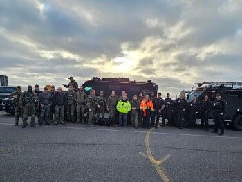 Several members of a SWAT team posing for a photo at Vashon terminal with some of their vehicles behind them