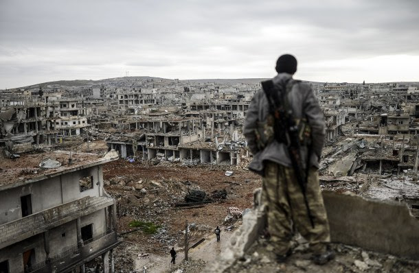 -- AFP PICTURES OF THE YEAR 2015 -- Musa, a 25-year-old Kurdish marksman, stands atop a building as he looks at the destroyed Syrian town of Kobane, also known as Ain al-Arab, on January 30, 2015. Kurdish forces recaptured the town on the Turkish frontier on January 26, in a symbolic blow to the jihadists who have seized large swathes of territory in their onslaught across Syria and Iraq. AFP PHOTO/BULENT KILIC