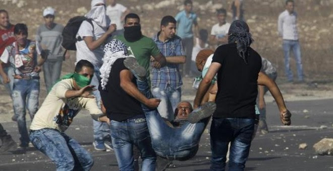Manifestantes palestinos cargan con un compañero herido por disparos israelíes en una manifestación en el checkpoint de Howara, cerca de la ciudad de Nablus, Cisjordania.- EFE/EPA/ALAA BADARNEH