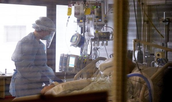 Registered nurse Andraya Zelle treats a patient in the COVID intensive care unit at UW Medical Center-Montlake in Seattle. The deadliest month of the coronavirus outbreak in the U.S. drew to a close with certain signs of progress: COVID-19 cases and hospitalizations are trending downward, while vaccinations are picking up speed. (AP Photo/Elaine Thompson, File)