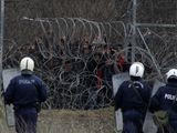 Greek riot police guard as migrants stand on a fence as they try to enter Greece from Turkey at the Greek-Turkish border in Kastanies on Wednesday, March 4, 2020. Facing a potential wave of nearly a million people fleeing fighting in northern Syria, Turkey has thrown open its borders with Greece to thousands of refugees and other migrants trying to enter Europe, and has threatened to send &quot;millions&quot; more. (AP Photo/Giannis Papanikos)