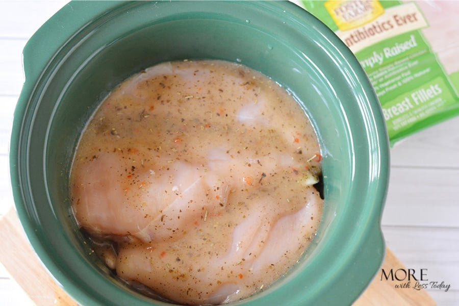 Adding chicken to crockpot to make Slow Cooker Chicken with Rosemary and White Beans recipe