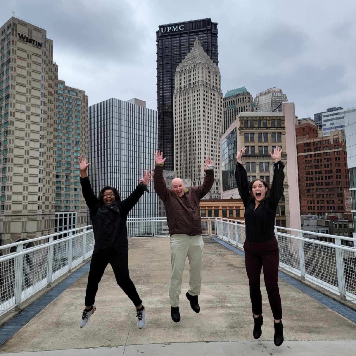 GA Staff jumping for joy in front of the Pittsburgh Skyline