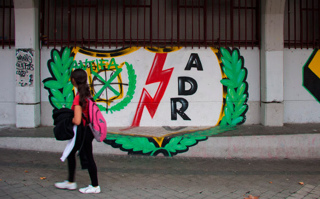 Una niña pasa por delante de un escudo del Rayo pintado en la fachada del estadio de Vallecas.