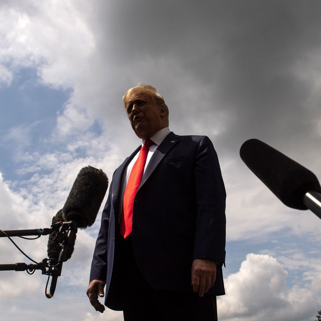 President Donald Trump speaking in to microphones against a cloudy background