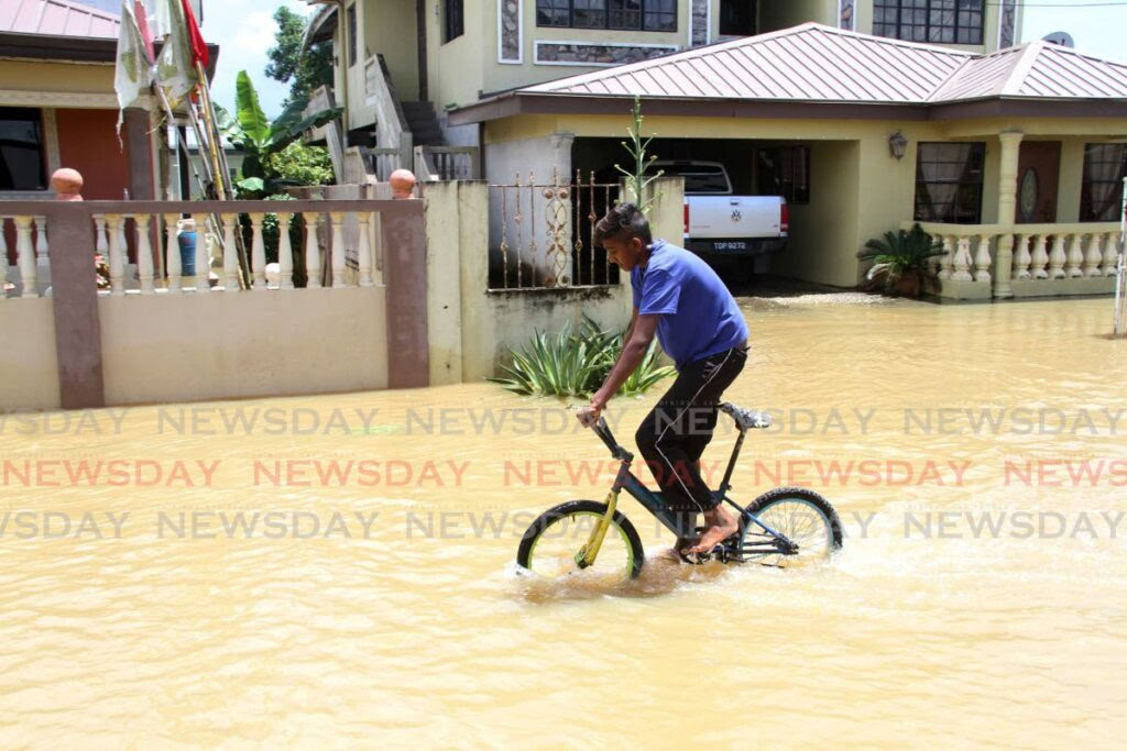 A boy joyrides through floodwaters in Kelly Village, Caroni in August 2021. - Angelo Marcelle