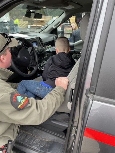 Ranger Laymon showing a child the inside of the Forest Ranger truck