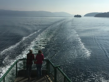 Photo of people on outdoor deck of a ferry looking at another ferry in waters off San Juan Islands