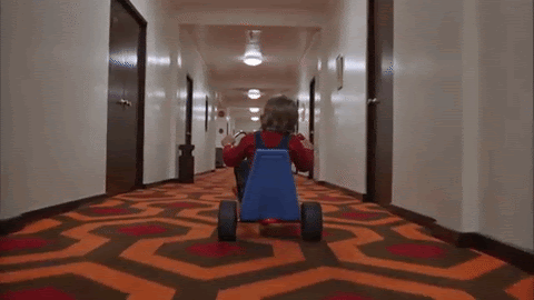 scene from The Shining with Jack riding a scooter down a coridoor 