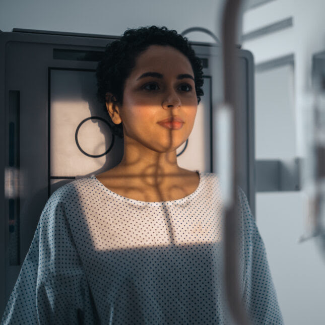 Photo of a woman standing in front of an x-ray machine -- cancer coverage for STAT