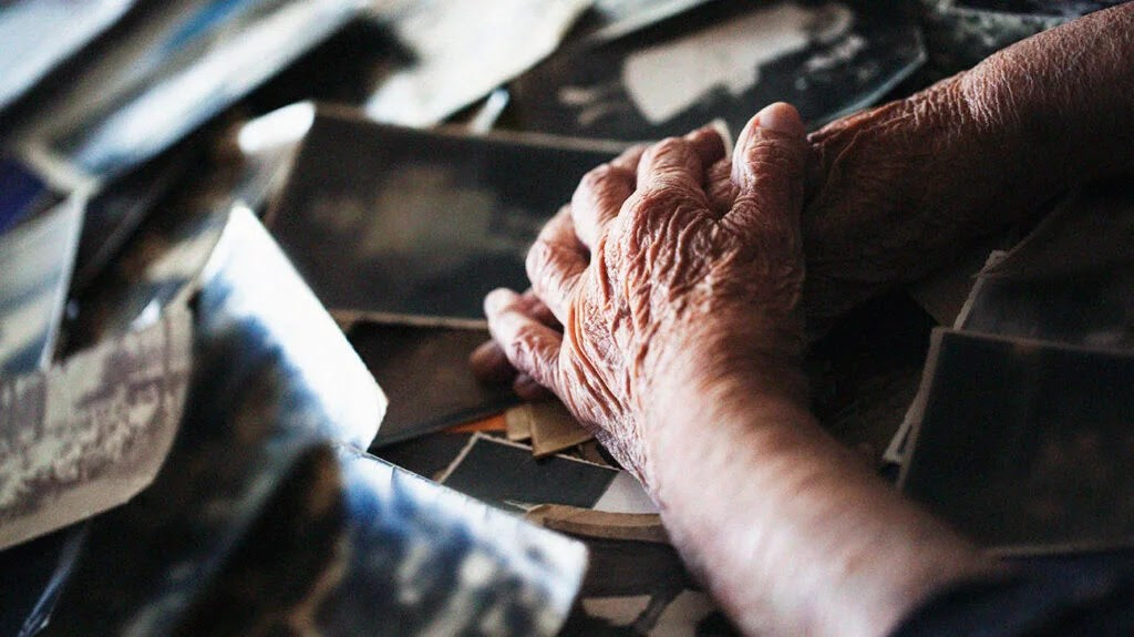 Close-up image of a person's hands resting on old black and white photographs