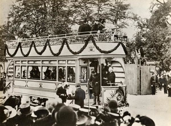 Photo of a crowd of people around an electric tram draped in decorations