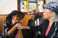 Two older African-American women and one African-American man sitting in a church
