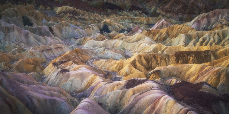 A view of multi-colored earth in an eroded maze of hills and valleys.