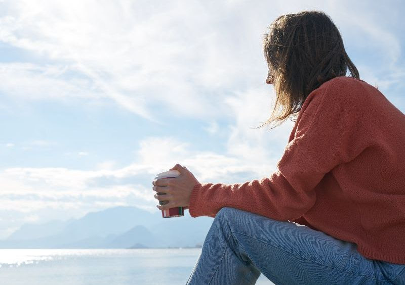 Woman sitting in front of body of water