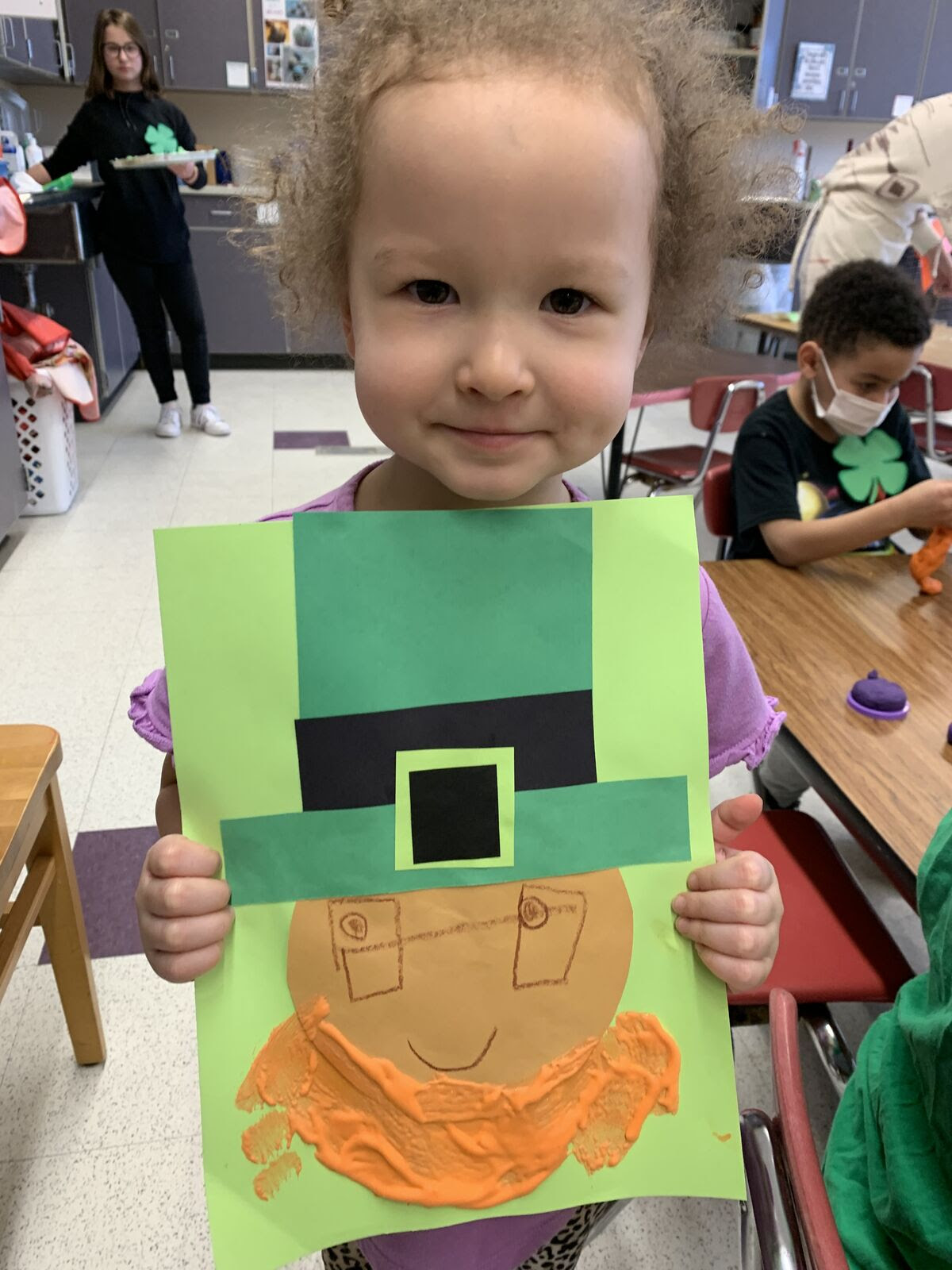 student smiling while holding leprechaun craft