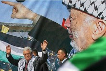 Mahmoud Abbas, acting leader of the PA, speaks in front of a banner of Yasser Arafat.