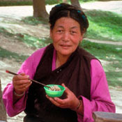 Asian woman eats using chopsticks seated at an outdoor table