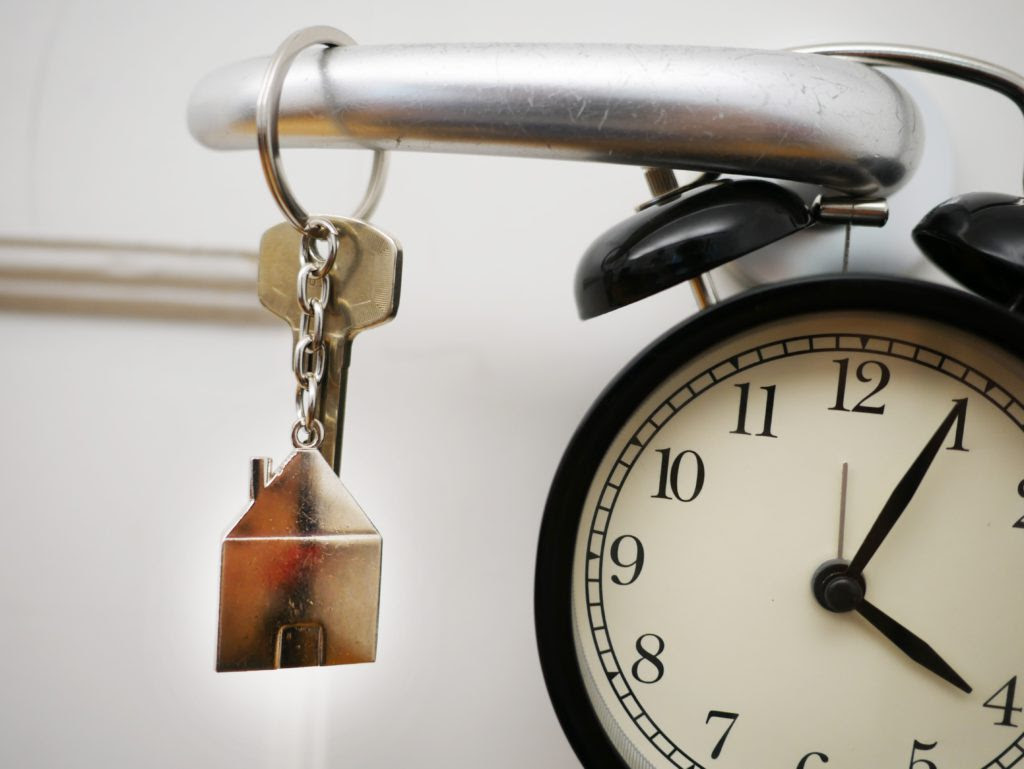 llaves en la manija de una puerta junto a un reloj despertador