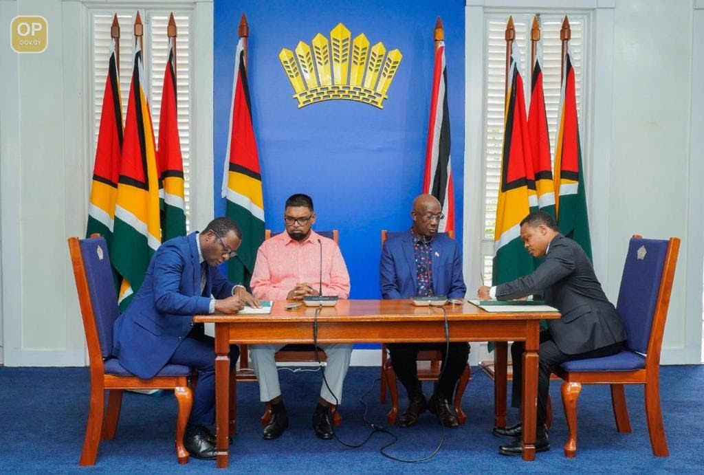 Guyana president Dr Irfaan Ali, second from left, and Prime Minister Dr Keith Rowley, second from right, witness the signing of a memorandum of understanding (MOU) between their countries by Guyana foreign affairs minister Hugh Todd, left, and TT's Caricom and Foreign Affairs Minister Dr Amery Browne on Sunday in Guyana. Photo courtesy the Office of the Prime Minister