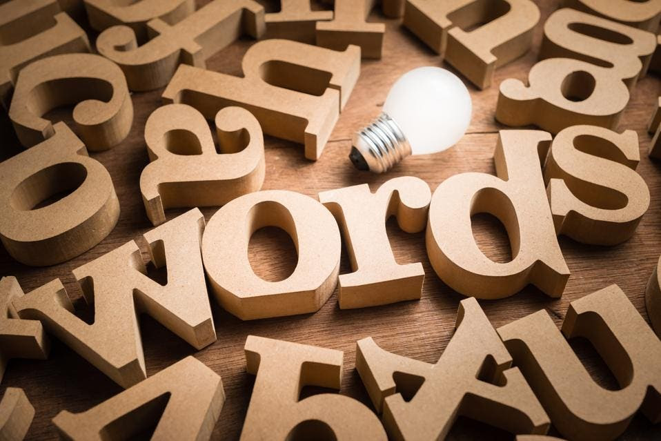 A photo of wooden letters on a table with a light bulb. One word says: word