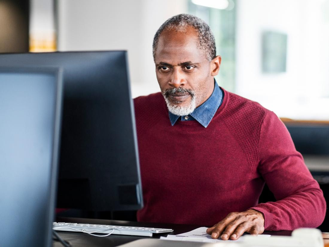 a very serious man sat at his desk at work.