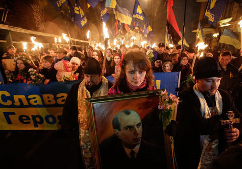 Jeune femme brandissant un portrait de Stepan Bandera.