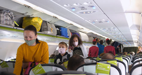 Pasajeros con mascarilla dentro de la cabina de un avión.