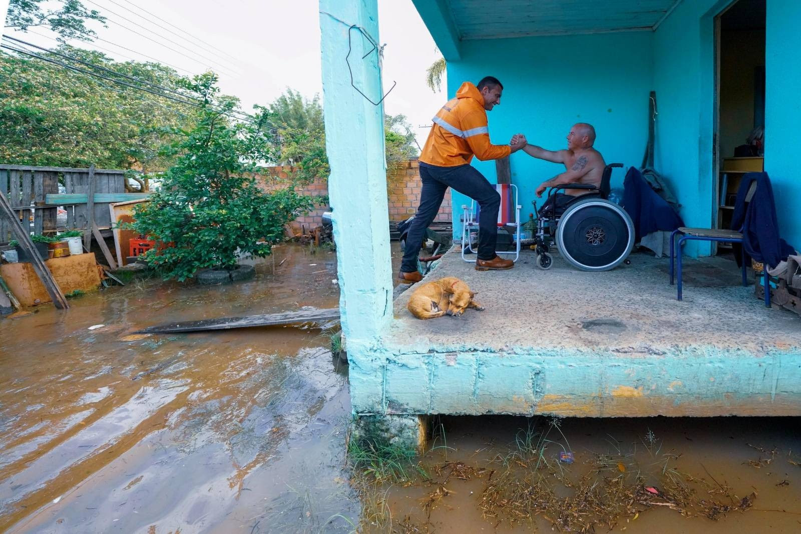 Funcionário da Defesa Civil de Porto Alegre retira homem em cadeira de rodas de casa alagada. Porto Alegre não tem plano para lidar com os efeitos das mudanças climáticas