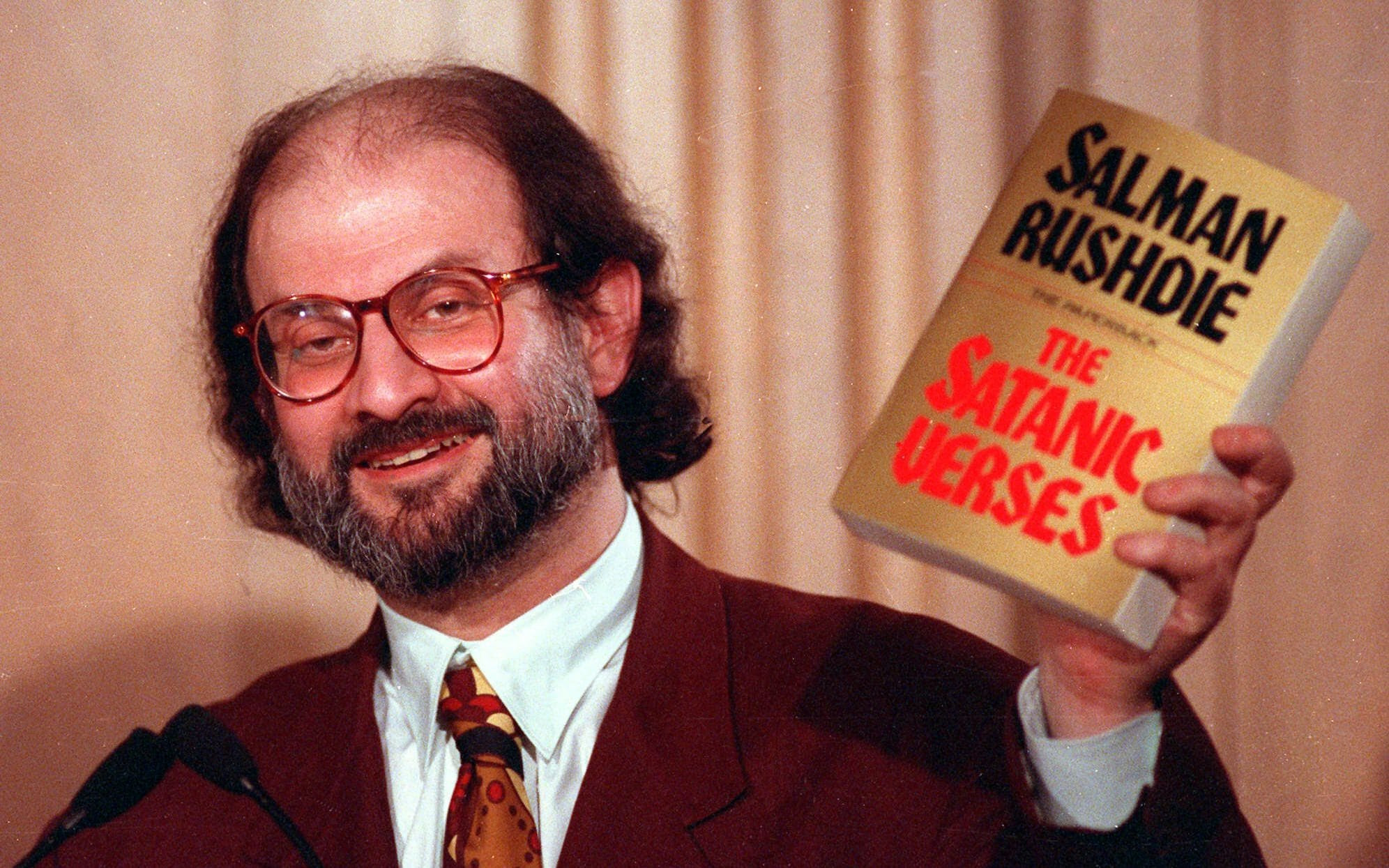 Salman Rushdie holding a copy of The Satanic Verses