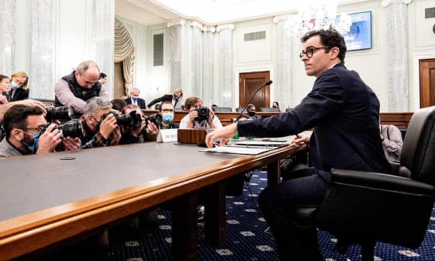 Adam Mosseri sits at table with photographers on other side