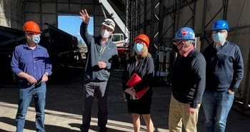 Photo of five people outside at a shipyard