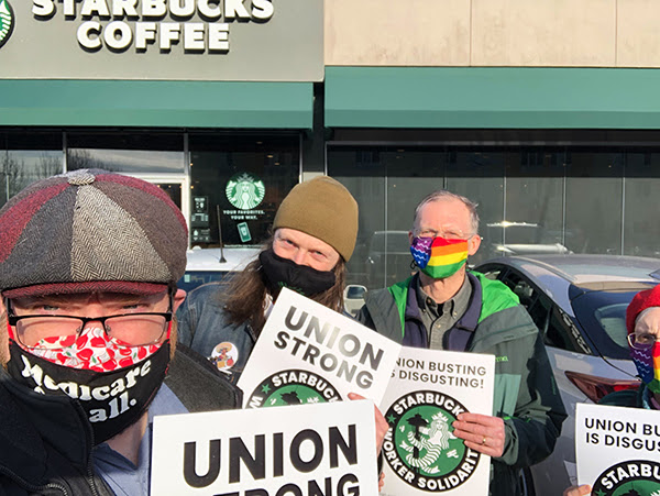 A photo of Jason Call and several labor organizers holding pro-union signs from Starbucks Worker Solidarity outside of a Starbucks store in Washington’s 2nd congressional district.