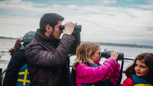 Family members peer at seals through binoculars on a 2022 Save The Bay Seal Tour