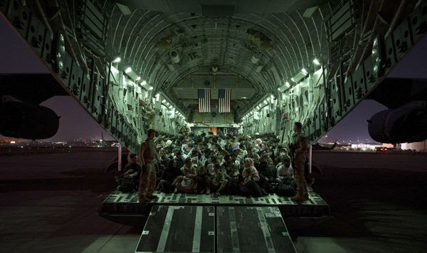 In this image provided by the U.S. Air Force, U.S. Air Force aircrew, assigned to the 816th Expeditionary Airlift Squadron, assist qualified evacuees boarding a U.S. Air Force C-17 Globemaster III aircraft in support of the Afghanistan evacuation at Hamid Karzai International Airport, Kabul, Afghanistan, Saturday, Aug. 21, 2021. (Senior Airman Taylor Crul/U.S. Air Force via AP)