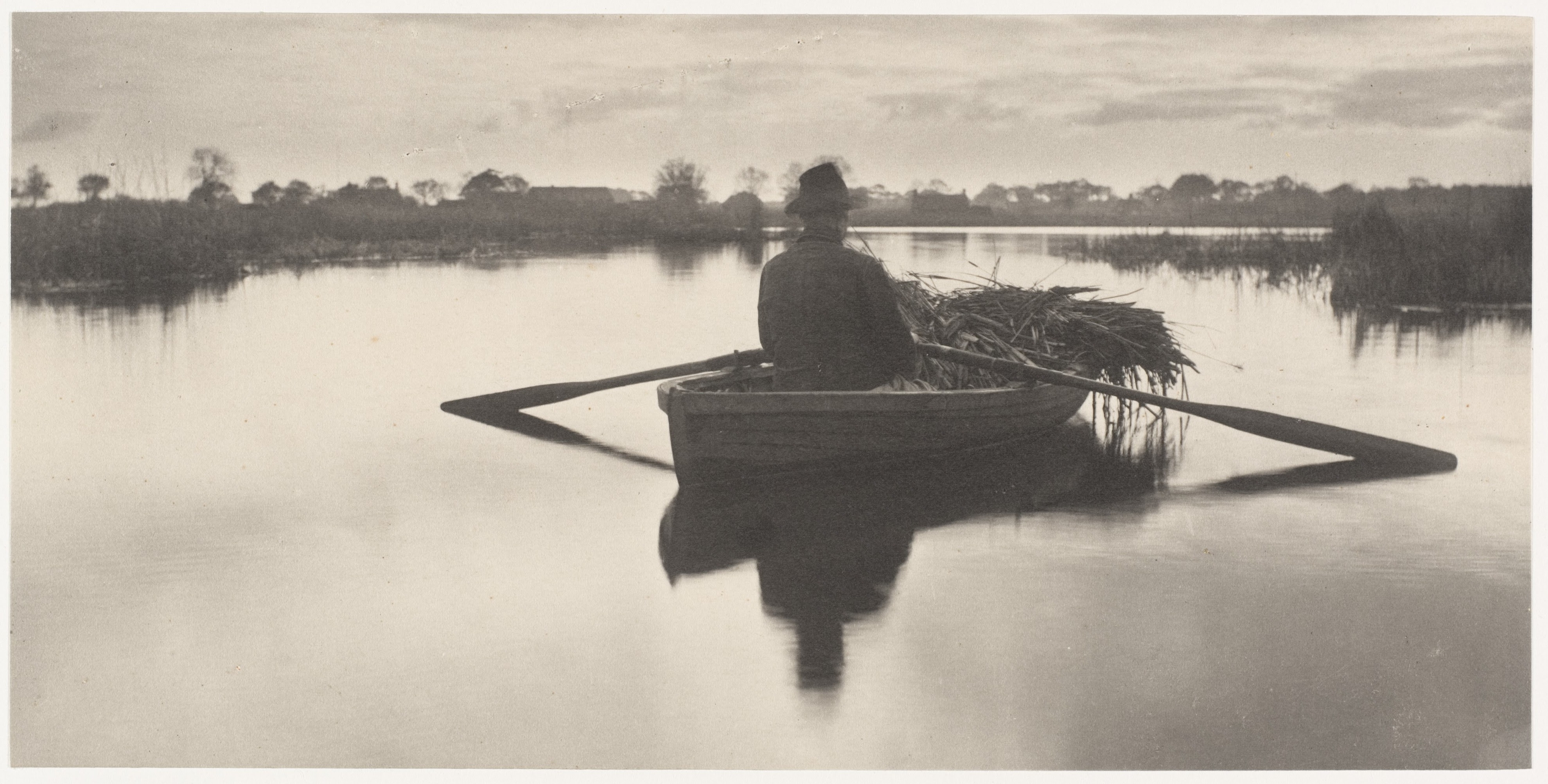 Black and white photograph of a man on a rowboat.