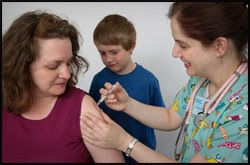 The figure above is a photograph showing a nurse administering a vaccination to a patient, as the patient’s son watches.