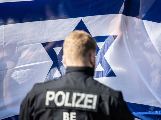 Israeli flag Germany BERLIN, GERMANY - JUNE 01: A German policeman stands in front of counter demonstrators waving an Israeli flag as the annual Al-Quds march pass by (not pictured) on June 1, 2019 in Berlin, Germany. Critics accuse the Al-Quds marchers of anti-Semitism Quds Day was originally held in Iran and spread …