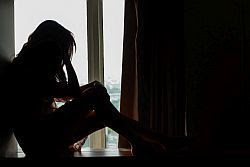 silhouette photo of a person sitting on the floor with their head in their hands