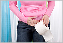 A woman holding her stomach and a roll of toilet paper.