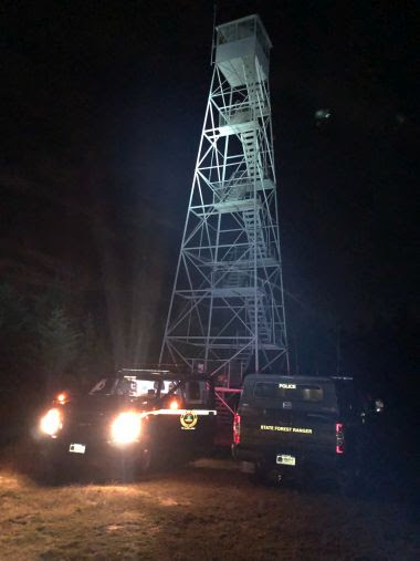 night-time photo of fire tower and Forest Ranger vehicles